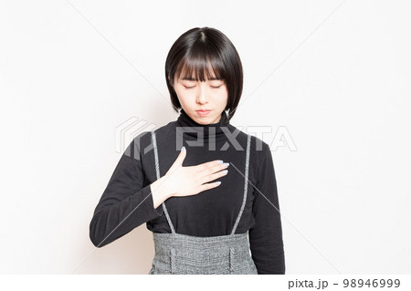 胸に手を当てている若い女性 98946999