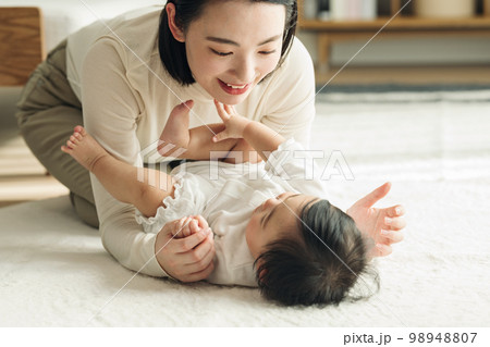 家のリビングで赤ちゃんをあやすママ 98948807