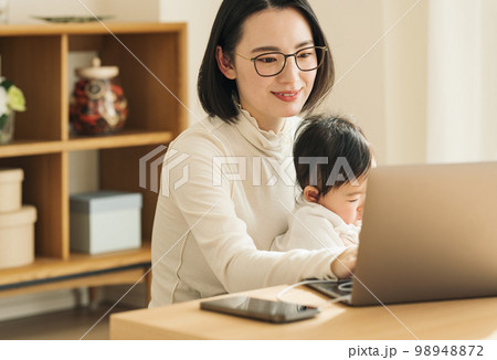 赤ちゃんを抱っこしながらパソコンを使う主婦 赤ちゃんを抱っこしながらパソコンを使う主婦 98948872