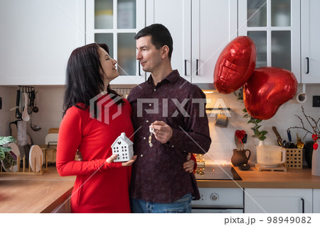 Man and woman in love date at home in kitchen with keys of house. Valentine's Day, happy couple, love story. Love nest, mortgage, relocation, purchase, real estate, housing for young family 98949082