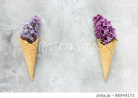 Fresh pink and purple lilac flowers in waffle ice cream cone on gray background. Flat lay, top view, copy space, spring abstract floral background. 98949172