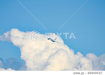 積乱雲付近を飛んでいる旅客機 98949587