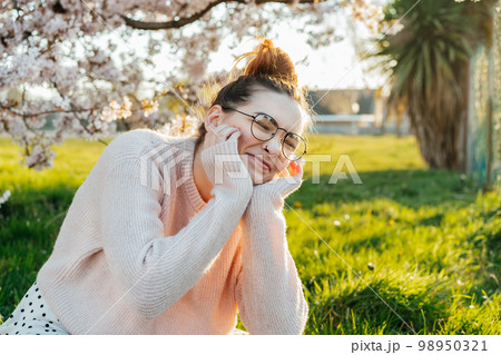 Portrait of young laughing caucasian hipster girl in glasses with pimples, acne on her face. Body positivity and diversity. Teenage skincare problems. Generation Z girl enjoy spring mood. 98950321