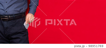 A man pulls out a package with a condom on a red background. Protected sex, barrier methods of contraception, prevention of sexually transmitted infections. Banner place for copy space text 98951769