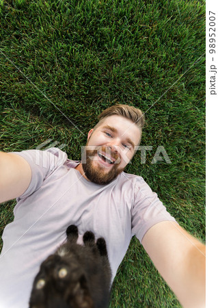Man with little kitten lying and playing on grass - friendship love animals and pet owner concept 98952007