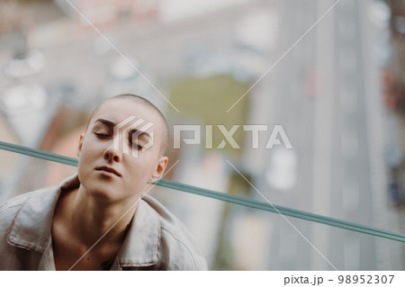 High angle view of young unhappy woman with cancer sitting in a window. 98952307
