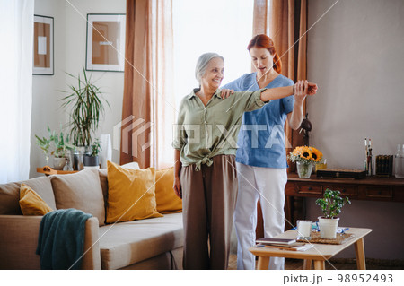 Nurse exercising with senior woman at her home, concept of healthcare and rehabilitation. Nurse exercising with senior woman at her home, concept of healthcare and rehabilitation. 98952493