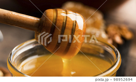 Honey on wooden honey-dipper closeup food background 98952694