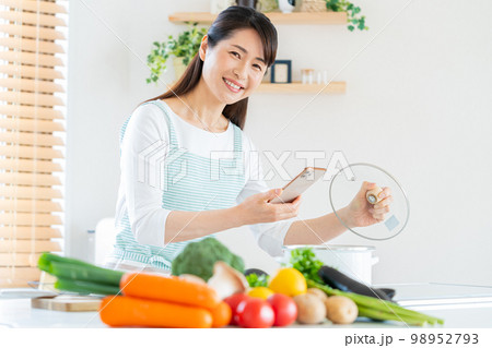 キッチンで調理する笑顔のミドル女性 98952793