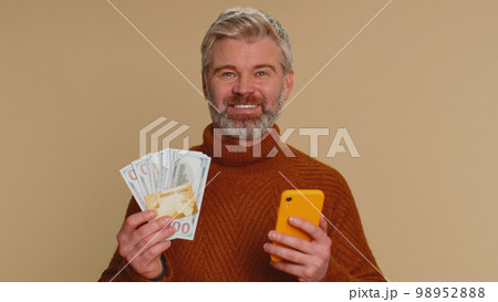 Senior man using credit bank card and smartphone while transferring money purchases online shopping 98952888