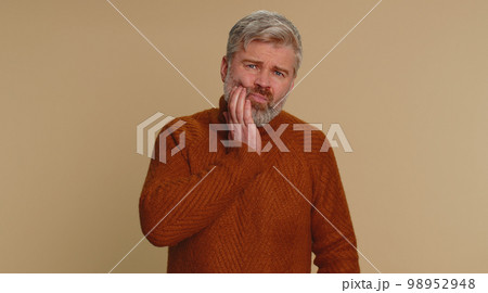 Man touching cheek suffering from toothache cavities or gingivitis waiting for dentist appointment Man touching cheek suffering from toothache cavities or gingivitis waiting for dentist appointment 98952948