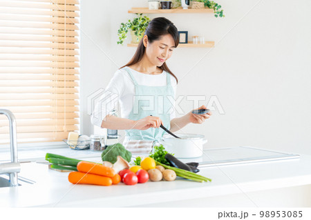 キッチンで調理する笑顔のミドル女性 98953085