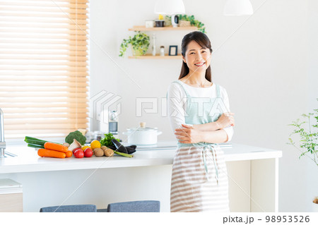 キッチンに立つ笑顔のミドル女性 98953526