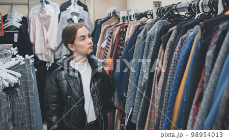 A young girl choosing and looking at clothes in the store. A young girl choosing and looking at clothes in the store. 98954013
