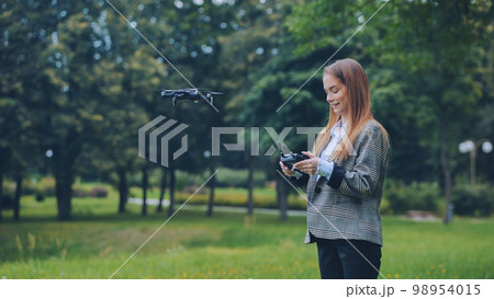 A cute girl controls a drone in the park. A cute girl controls a drone in the park. 98954015