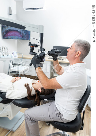 Dentist using dental microscope treating patient with braces in dental office 98954249