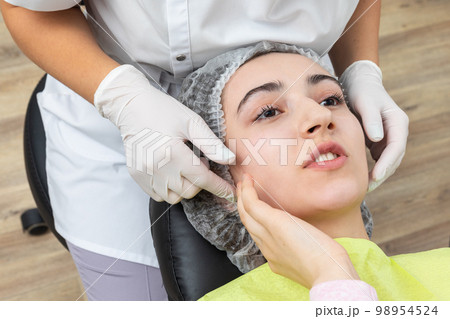 Dentist looks at a jaw of female patient checking the bite 98954524