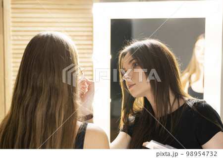 Make-up artist working with brush on model face. Portrait of young blonde woman in beauty salon interior. Process of making makeup. Applying toner to skin. Make-up artist working with brush on model face. Portrait of young blonde woman in beauty salon interior. Process of making makeup. Applying toner to skin. 98954732
