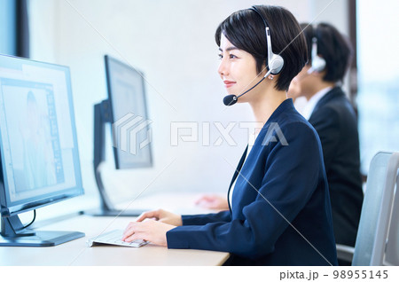 オフィスでヘッドセットをつけて対応するオペレーターの女性 98955145