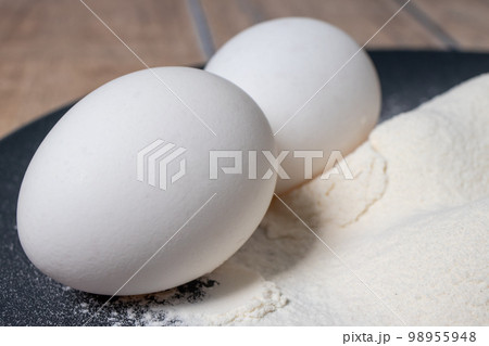 Wheat white flour and eggs on a black plate. Making bread and baked goods. Cooking at home 98955948