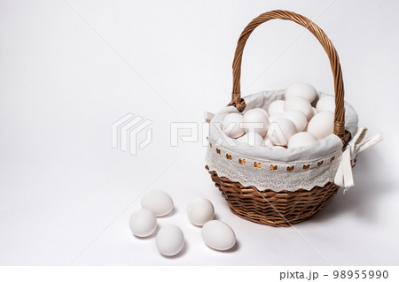 A lot of chicken white eggs in a wicker beautiful basket of twigs. A lot of chicken white eggs in a wicker beautiful basket of twigs. 98955990