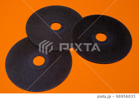 A cut-off wheel for a grinder tool on a orange background with a place for copyspace text. Tools for construction and repair, workshop. 98956035