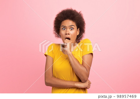 Frightened young black curly lady with open mouth scared and looking at camera Frightened young black curly lady with open mouth scared and looking at camera 98957469