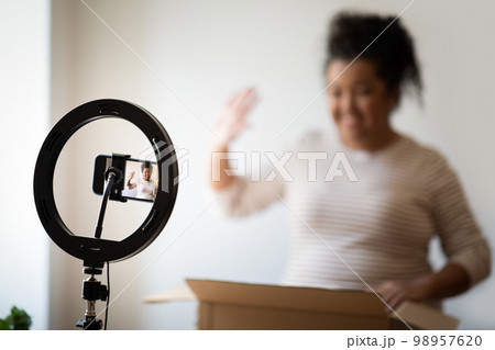 Cheerful overweight lady streaming while opening delivery. Blogging concept 98957620