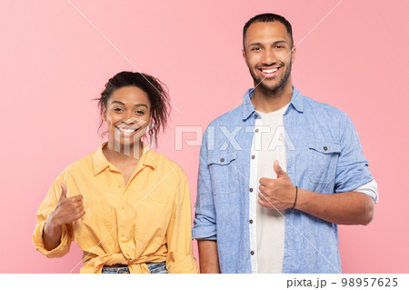 Great choice concept. Positive black couple gesturing thumbs up at camera, recommending something, pink background 98957625