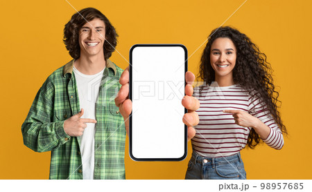 Mobile Mockup. Happy Young Couple Pointing At Cellphone With Blank Screen Mobile Mockup. Happy Young Couple Pointing At Cellphone With Blank Screen 98957685