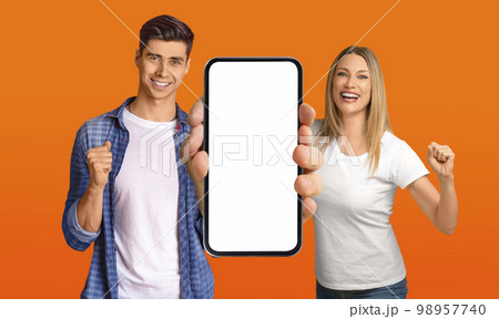 Man And Woman Holding Big Blank Smartphone And Celebrating Success 98957740