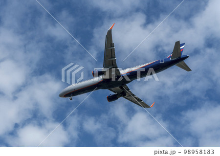 A white blue passenger plane with two engines against a cloudy sky. Russia Sochi July 2022. 98958183