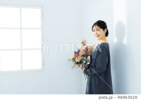 花束を持つグレーのワンピースの女性 98963020