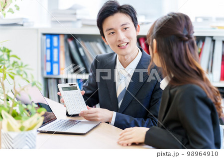 電卓を使って打ち合わせをする人々 98964910