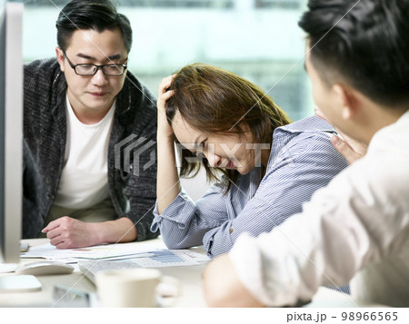 frustrated asian businesswoman getting comfort from colleagues while discussing business in office 98966565