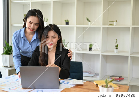Kind and happy Asian female boss or manager supports her female assistant 98967439