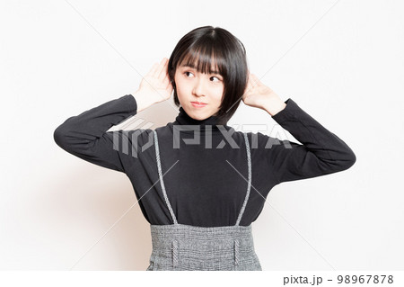聞き耳を立てている若い女性 聞き耳を立てている若い女性 98967878