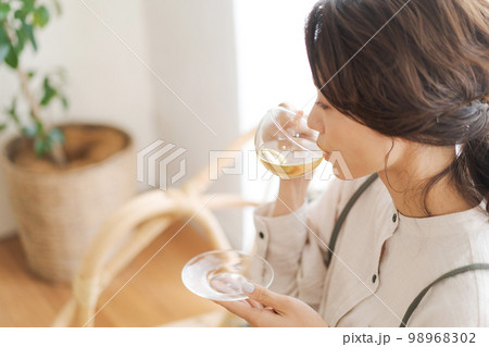 温かい飲み物を飲む女性 98968302