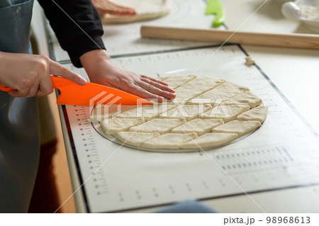 Side view of cutting dough with a plastic knife on a silicone baking mat 98968613