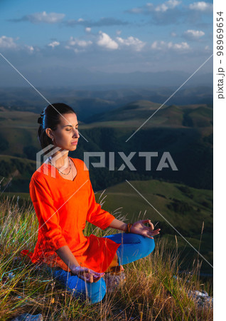 young yogi woman practicing meditation with closed eyes in lotus position at sunset 98969654
