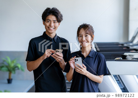 スマホを持つジムのインストラクター 98972122
