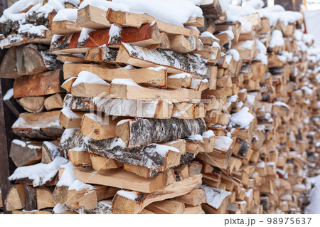 Stacked firewood covered with white snow, wood for kindling Stacked firewood covered with white snow, wood for kindling 98975637