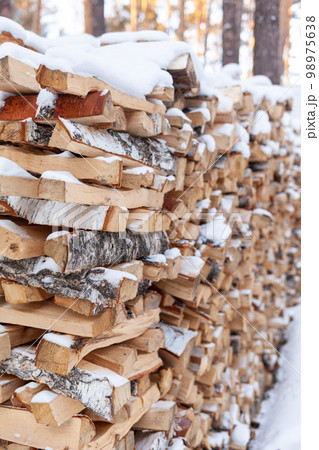 Stacked firewood covered with white snow, wood for kindling 98975638