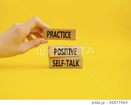 Practice positive self-talk symbol. Concept words Practice positive self-talk on wooden blocks. Businessman hand. Beautiful yellow background. Business concept. Copy space 98977064