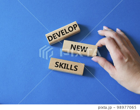 Develop New skills symbol. Concept word Develop New skills on wooden blocks. Businessman hand. Beautiful blue background. Business and Develop New skills concept. Copy space Develop New skills symbol. Concept word Develop New skills on wooden blocks. Businessman hand. Beautiful blue background. Business and Develop New skills concept. Copy space 98977065
