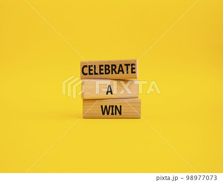 Celebrate a win symbol. Concept words Celebrate a win on wooden blocks. Beautiful yellow background. Business and Celebrate a win concept. Copy space. 98977073