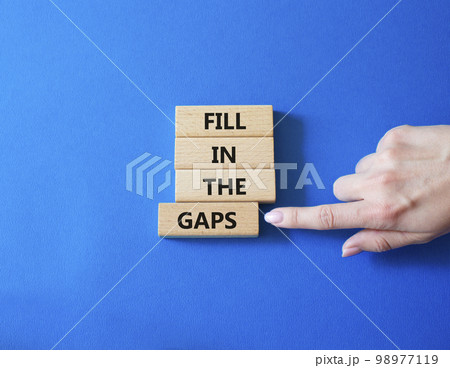 Fill in the gaps symbol. Concept words fill in the gaps on wooden blocks. Beautiful blue background. Business and fill in the gaps concept. Copy space. Fill in the gaps symbol. Concept words fill in the gaps on wooden blocks. Beautiful blue background. Business and fill in the gaps concept. Copy space. 98977119