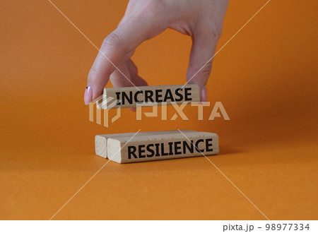 Increase resilience symbol. Wooden blocks with words Increase resilience. Businessman hand. Beautiful orange background. Business and Increase resilience concept. Copy space. 98977334