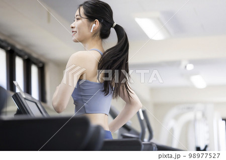 フィットネスジムのランニングマシンで走る若い女性 フィットネスジムのランニングマシンで走る若い女性 98977527