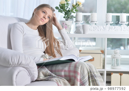Young woman with a book in cozy armchair Young woman with a book in cozy armchair 98977592